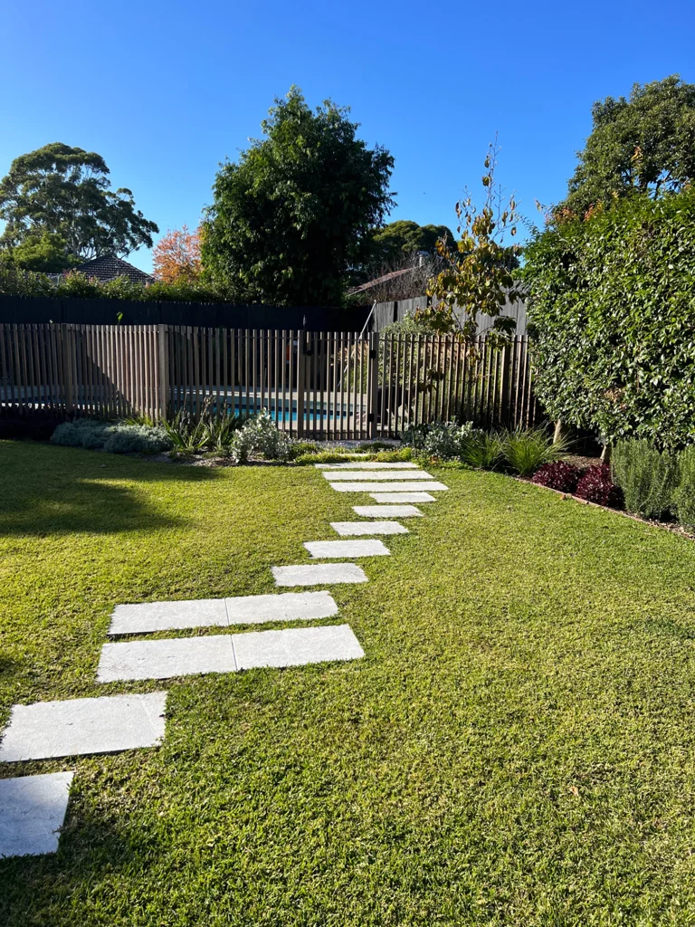 Pale stepping stones leading across the lawn towards the pool