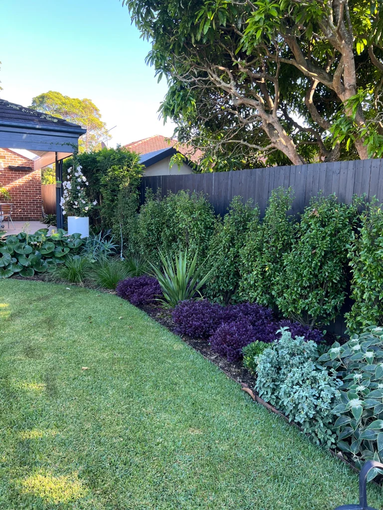 Lawn framed by a layered garden border and established trees