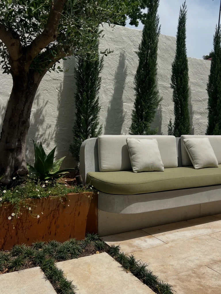 A tree and layered planting beside courtyard seating