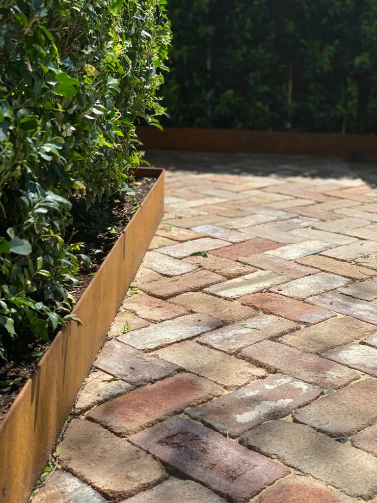 Brick paving in warm varied tones alongside garden planting