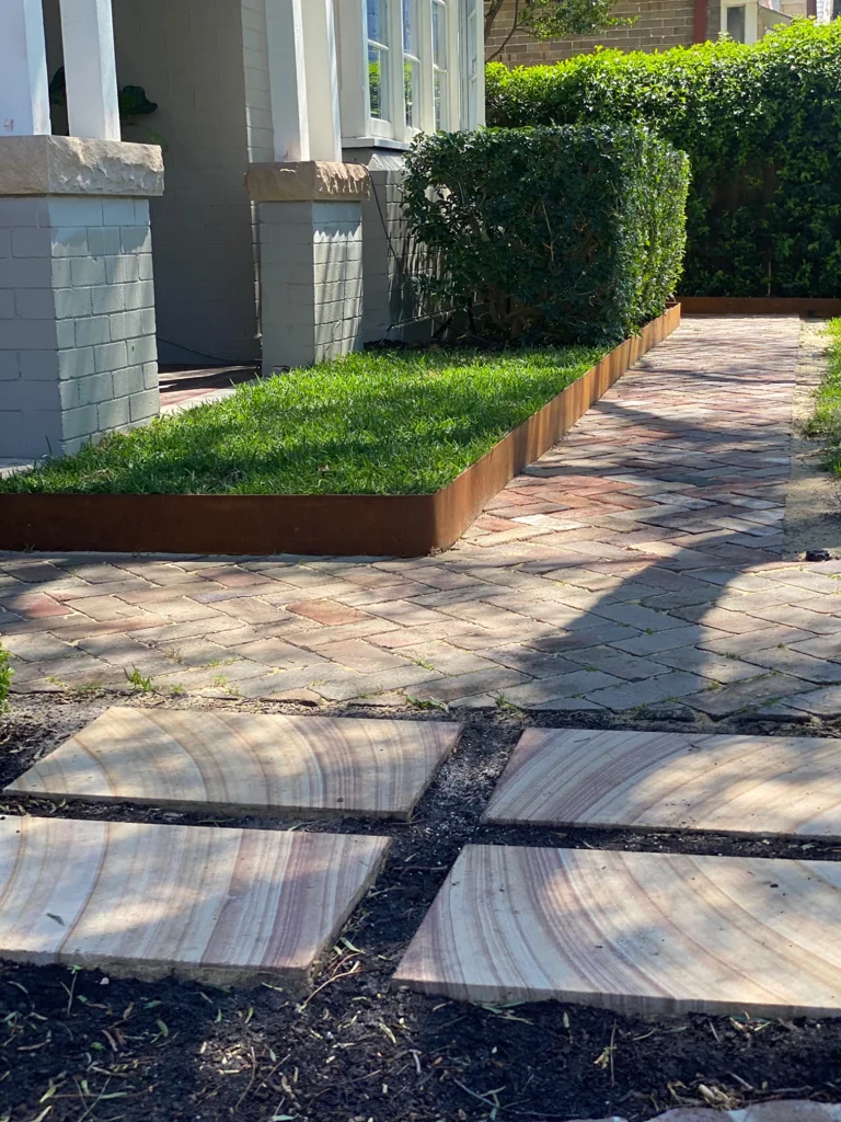 Brick path leading past clipped hedges and lawn