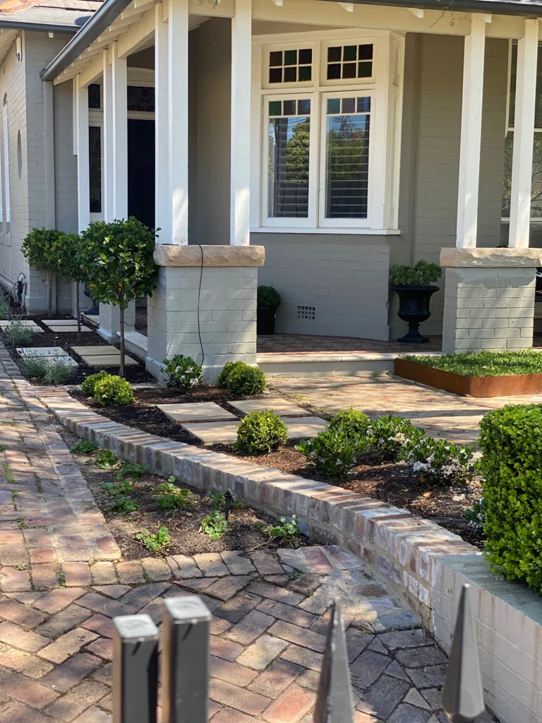 Curving brick path and planted borders beside the verandah