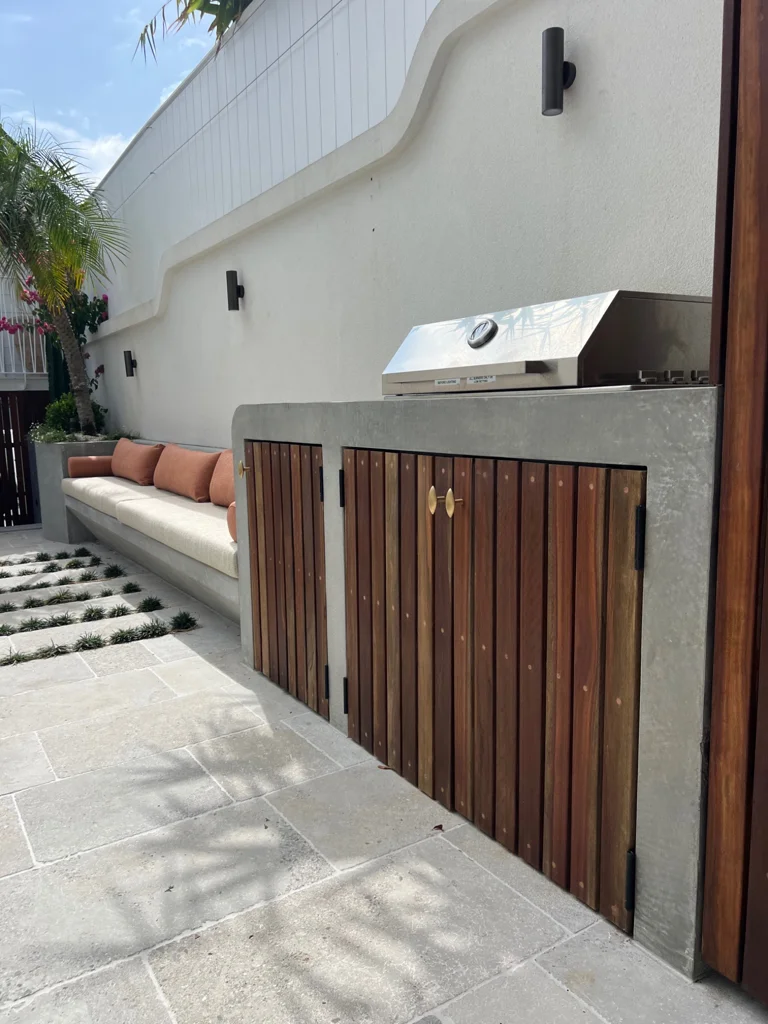 Outdoor barbecue and timber-fronted cabinetry beside courtyard seating
