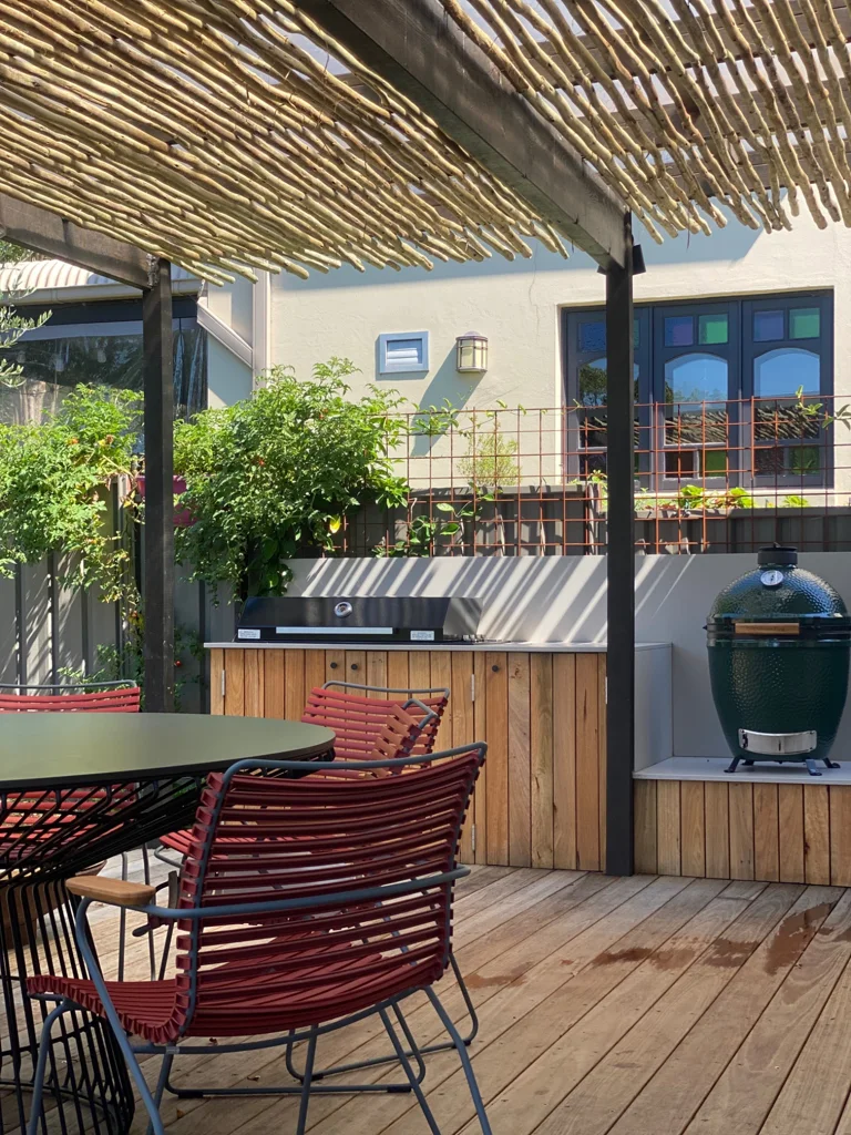 Outdoor dining and a timber-fronted barbecue beneath a slatted pergola