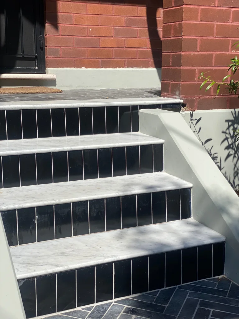 Dark tiled steps and patterned paving at the front entrance